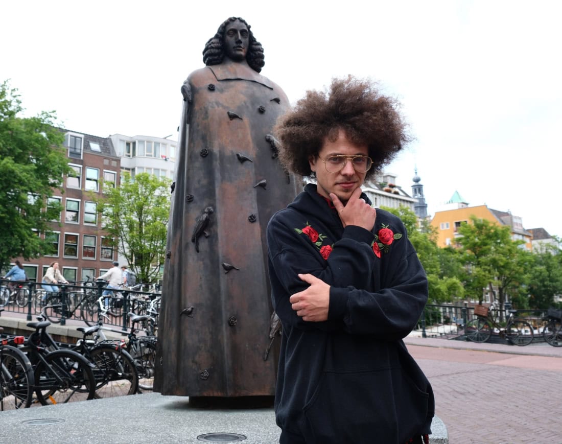 Rapper Benjamin Fro bij beeld van Spinoza in Amsterdam
